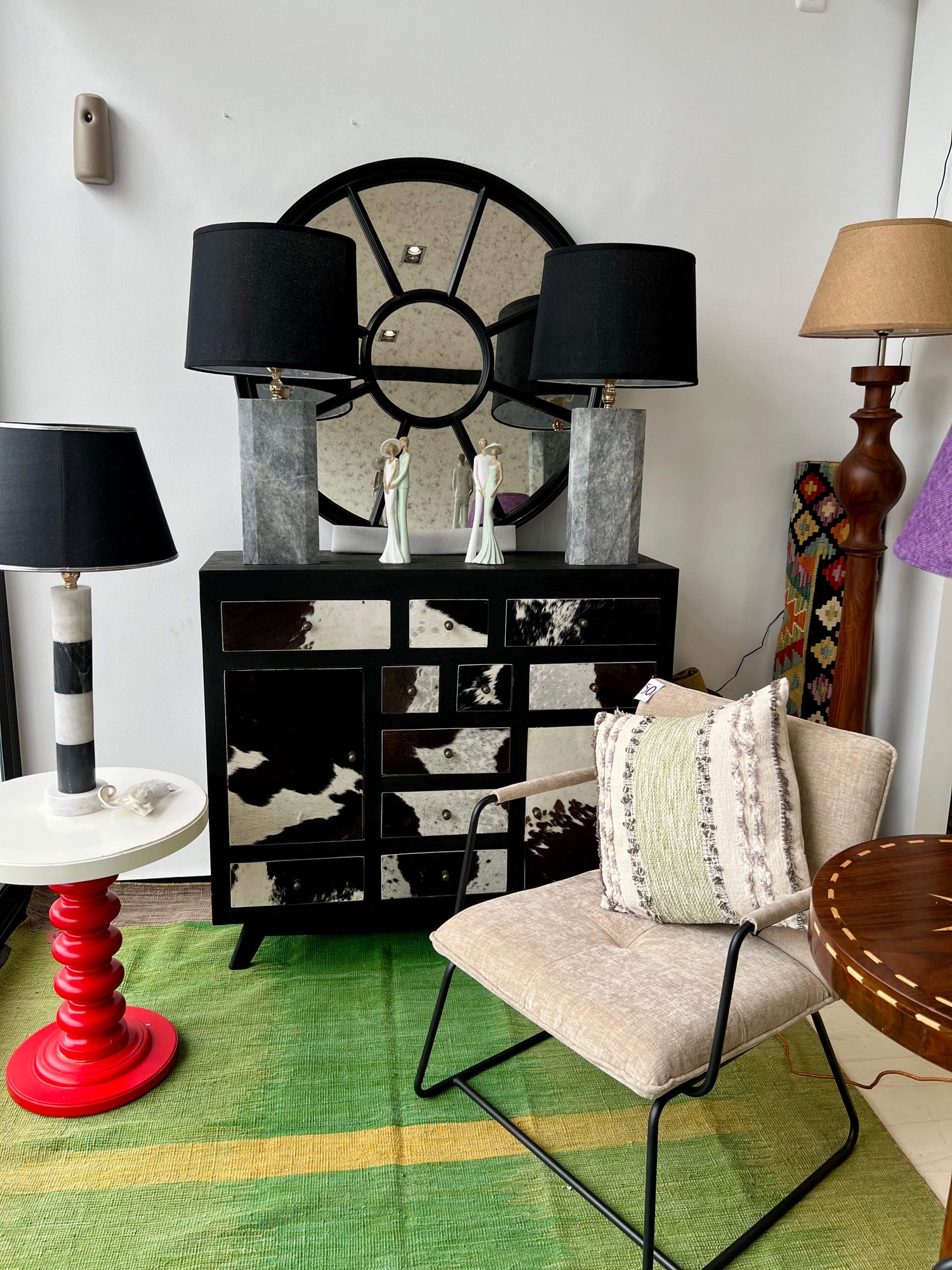 A corner of the showroom of Tradexx in Estepona, Spain showcasing a green and black themed home decor setup using natural marble lamps and a hand-knotted kilim.